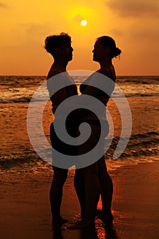 Silhouettes of a loving couple on the ocean shore.