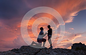 Silhouettes of a man making marriage proposal to his girlfriend