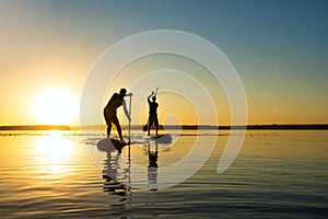 Silhouettes men, friends who are paddling on a SUP boards