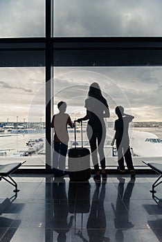 Silhouettes of mom with kids in terminal waiting for flight