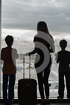 Silhouettes of mom with kids in terminal waiting for flight