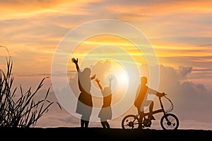 Silhouettes of Mother son and daughter playing at sunset evening sky background