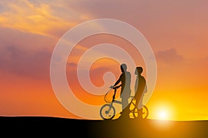 Silhouettes of mother and son playing at sunset evening sky background