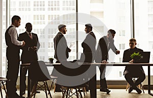 Silhouettes of people against the window. A team of young businessmen working and communicating together in an office