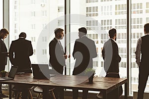 Silhouettes of people against the window. A team of young businessmen working and communicating together in an office