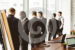 Silhouettes of people against the window. A team of young businessmen working and communicating together in an office