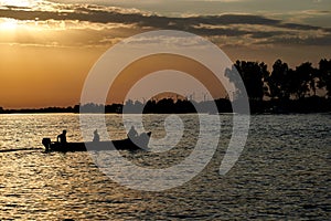 Silhouettes of people in a boat at sunset