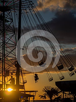 Silhouettes of people on the carousel. Concept of fun and entertainment. People on carousels at sunset. Resort town. Lunapark.