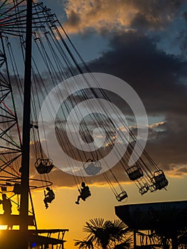 Silhouettes of people on the carousel. Concept of fun and entertainment. People on carousels at sunset. Resort town. Lunapark.