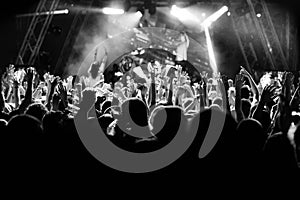 Silhouettes of people at a concert in front of the scene in bright light. Black and White