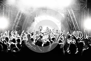 Silhouettes of people at a concert in front of the scene in bright light. Black and White