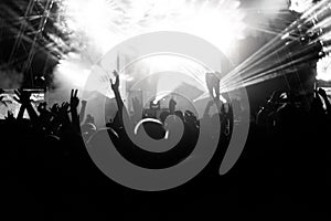 Silhouettes of people at a concert in front of the scene in bright light. Black and White