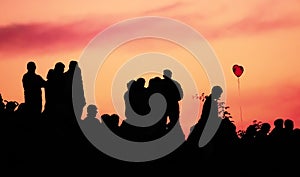 Silhouettes of people with different expressions on the embankment of the sea sunset