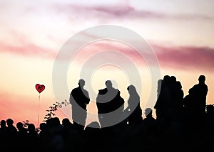 Silhouettes of people with different expressions on the embankment of the sea sunset