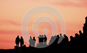 Silhouettes of people with different expressions on the embankment of the sea sunset