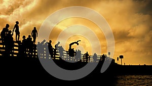 Silhouettes of people jumping of Beach Rd jaws bridge martha`s vineyard  Edgartown and Oak Bluffs sunset summer sky