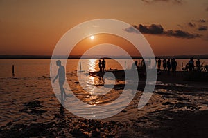 Silhouettes of people jumping in ocean and having fun at sunset. Tourism concept