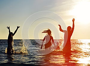 Silhouettes of people jumping in ocean