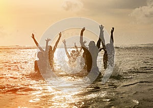 Silhouettes of people jumping in ocean