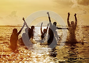 Silhouettes of people jumping in ocean