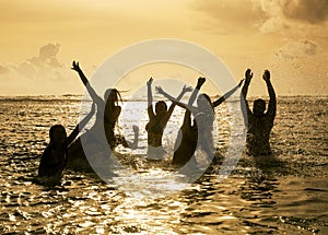 Silhouettes of people jumping in ocean