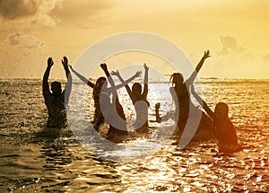 Silhouettes of people jumping in ocean