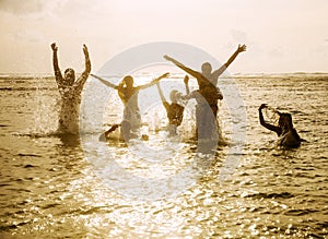 Silhouettes of people jumping in ocean