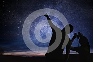 Silhouettes of people observing stars in night sky. Astronomy concept