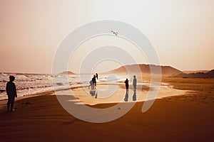 Silhouettes of people playing and flying a kite in sandy Golden Beach, Karpasia, Cyprus