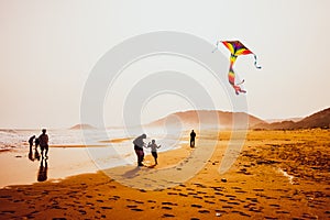 Silhouettes of people playing and flying a kite in sandy Golden Beach, Karpasia, Cyprus