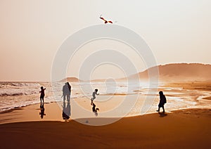 Silhouettes of people playing and flying a kite in sandy Golden Beach, Karpasia, Cyprus