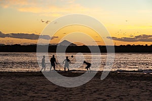 Silhouettes of People Playing Soccer on Beach at Sunset Time