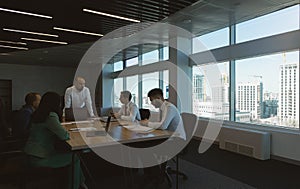 Silhouettes of people sitting at the table. Team of young business people working and communicating together in a modern