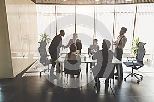 Silhouettes of people sitting at the table. A team of young businessmen working and communicating together in an office