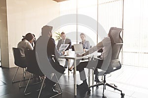 Silhouettes of people sitting at the table. A team of young businessmen working and communicating together in an office