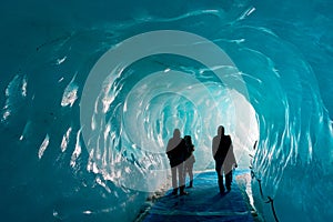 Silhouettes of people visiting thee ice cave of the Mer de Glace glacier, in Chamonix Mont Blanc Massif, The Alps France