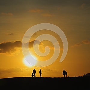 Silhouettes of people walk on the horizon