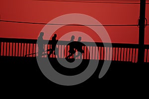 Silhouettes of people walking on a bridge