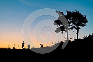 Silhouettes of people walking and running over the hill in beautiful colorful sunset. Outdoor activities