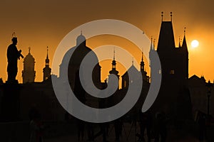 Silhouettes of Prague towers and statues on Charles bridge during sunrise