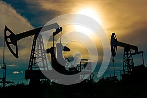 Silhouettes of pumpjacks on an oil wells against the background of an alarming sky photo