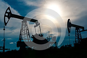 Silhouettes of pumpjacks on an oil wells against the background of an alarming sky photo