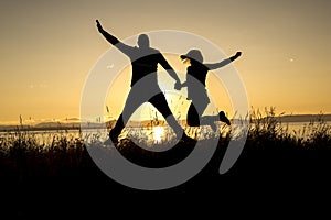 Silhouettes of romantic couple on tropical beach at sunset