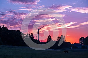 silhouettes of the rotating blades of a windmill propeller against the sunset sky. Wind energy production. Clean green energy
