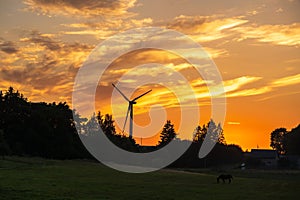 silhouettes of the rotating blades of a windmill propeller against the sunset sky. Wind energy production. Clean green energy