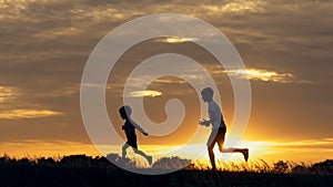 Silhouettes of running children in a field at sunset