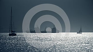 Silhouettes of sailboats and cargo ship near Gibraltar