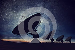 Silhouettes of satellite dishes or radio antennas against night sky. Space observatory