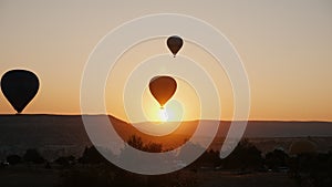 Silhouettes of several hot air balloons in the sky at sunrise