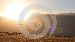 Silhouettes of Several Paragliders Against the Sun Setting Over Mountains